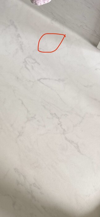 Bild av bortskavd yta på ett ljusgrått golv, markerad med röd ring, för reparation med lim.