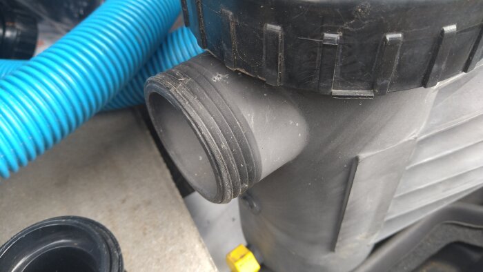 Anslutning på poolpump med gängor, bredvid en blå slang.