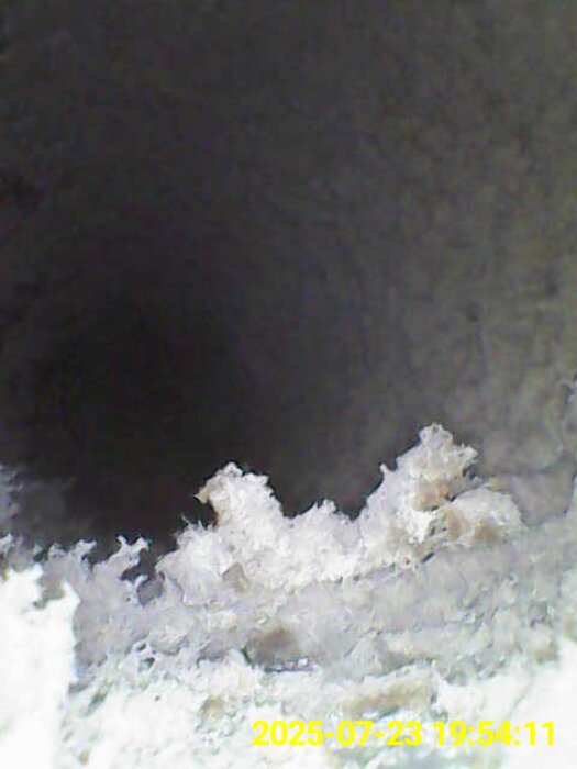 Bild från en endoskopikamera som visar insidan av en ventilationskanal med luddiga, dammiga ytor. Tidsstämpel syns längst ner.