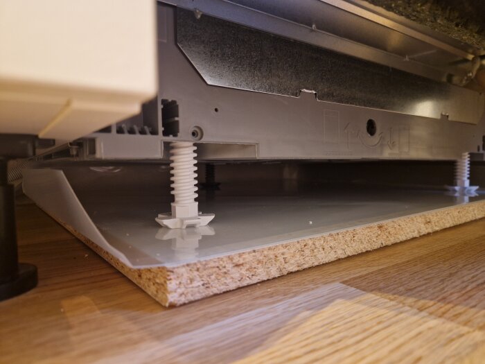 Underrede av en apparat placerad på en träskiva med ställbara ben.