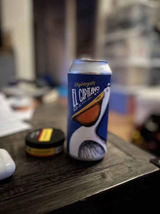 En burk med öl märkt Stigbergets "El Capitano" på ett träbord, med suddig bakgrund i ett rum.