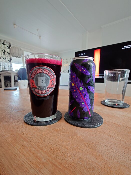 Ett glas syrlig öl med Omnipollo-burk, båda placerade på ett bord framför en tv, med dekoration i bakgrunden.