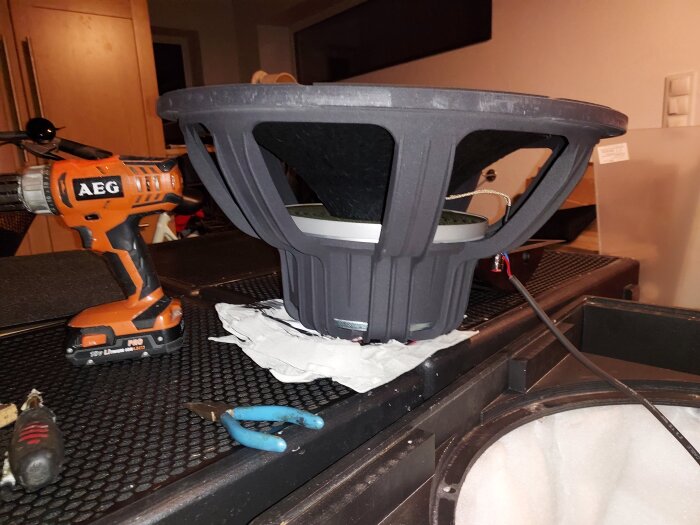 AEG borrmaskin och Faital Pro XL18 högtalarelement på ett bord, med verktyg i bakgrunden.