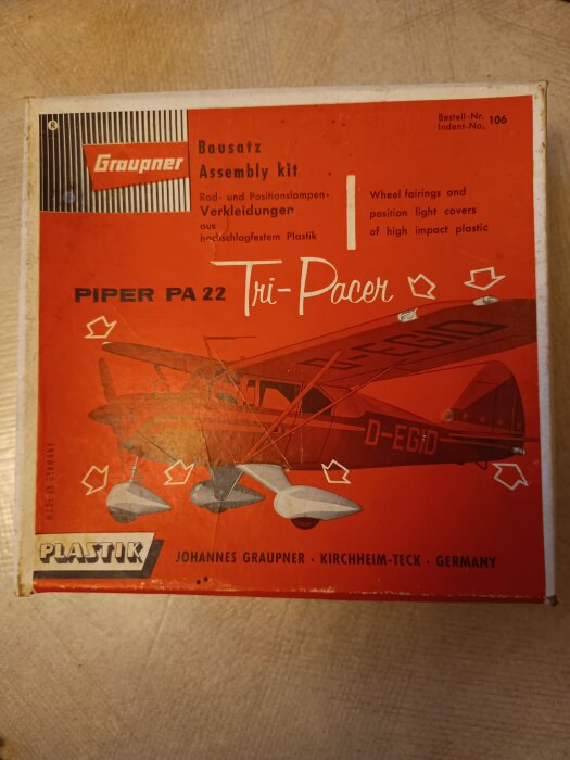Byggsats för Piper PA 22 Tri-Pacer modellflygplan från Johannes Graupner, i röd förpackning med text på tyska och engelska.