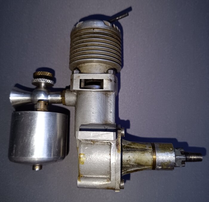 En motor till ett modellflygplan, troligen med glödstift, visad mot en mörk bakgrund. Motorer av denna typ används traditionellt med metanol.