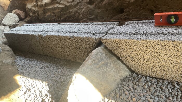 Murblock av lättklinker och tvättad makadam i en byggarbetsplats, med ett vattenpass placerat på toppen.