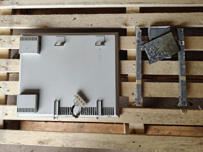 Elelement och dess avtagna komponenter placerade på en träpall, möjliga från 70- eller 80-talet, i en renoveringskontext.