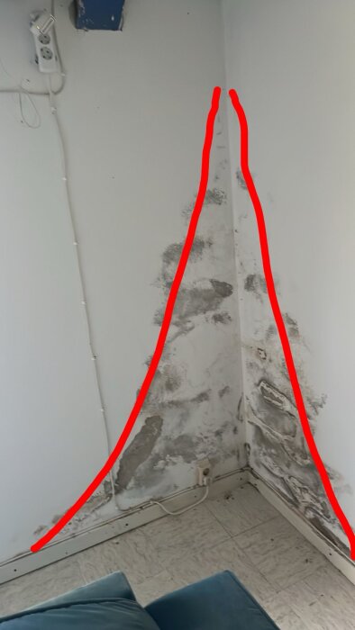 Fuktskadat hörn med fläckar och puts som lossnar, markerat med röda linjer, visar fuktproblem vid vägg i rum.