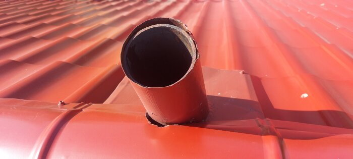 Rött tak med ett avloppsluftningsrör där plåten inte täcker rörets bas helt, vilket lämnar en glipa runt röret.