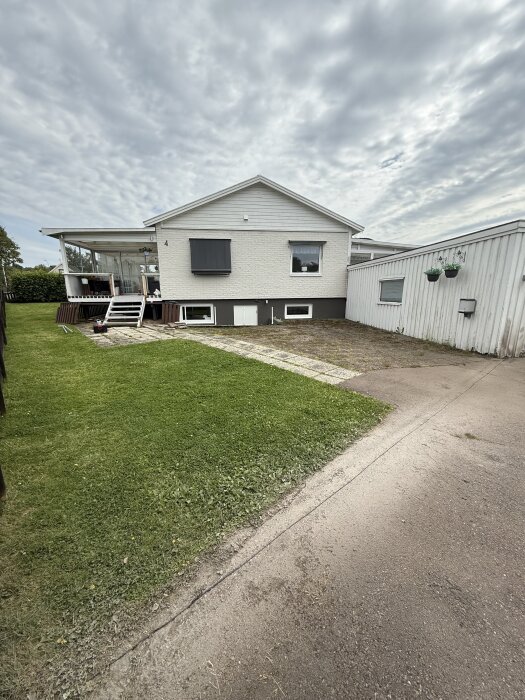 Rak linje kapad i asfalt mellan gräsmatta och garageuppfart vid ett vitt hus, förberett för grusläggning.