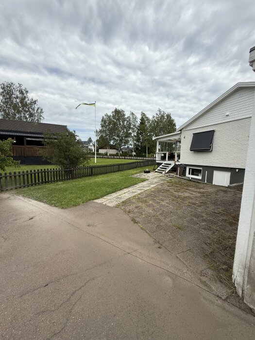 Kapat asfalt med rak linje intill gräsmatta och hus. Förberedelse för grävning, markduk och grusläggning.