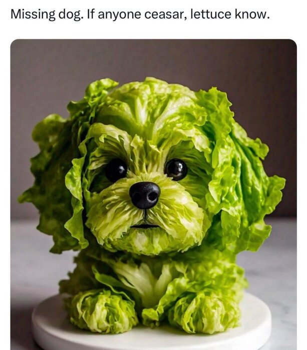 En skulptur av ett salladshuvud format som en hund med stora svarta ögon och nos på ett runt vitt fat.