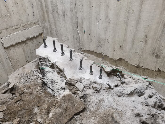 Krossat berg med bultade stavar och sluttande kant, inuti ett område med betongväggar.