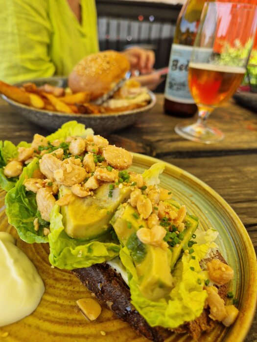 Avokado på gemsallad och hembakad kavring, toppad med Marconamandlar, med en Bedarö Bitter på ett bord vid Svedtiljas på Öja, Landsort.