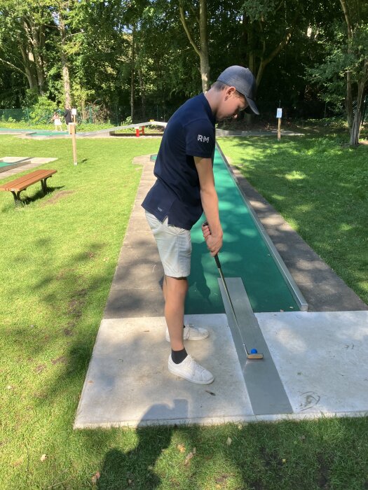 Person spelar minigolf på en bana i en grön park.