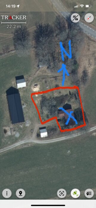 Satellitbild över en tomt med röd markering och blå pilar, visar potentiell husplacering och norrpil.