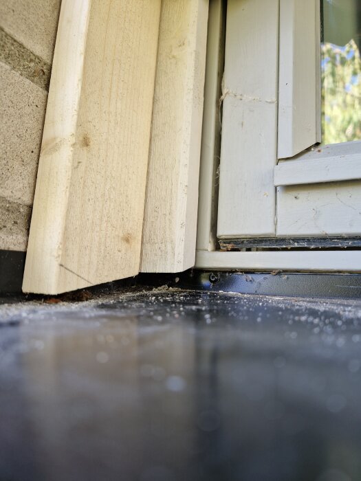 Gammalt fönster med nytt träramfoder monterat på en byggarbetsyta, redo för oljning och målning.