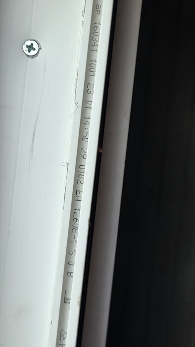 Närbild på en del av ett fönster med ett serienummer och skruv synligt, användaren söker efter tillverkare för att beställa reservdelar.