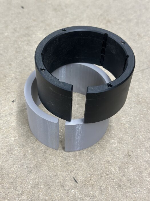 Svart och grå passring med slits för anpassning från 92mm till 65mm, på betongunderlag.