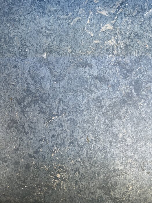 Gråblått marmorerat golv med varierande nyanser och subtila mönster.