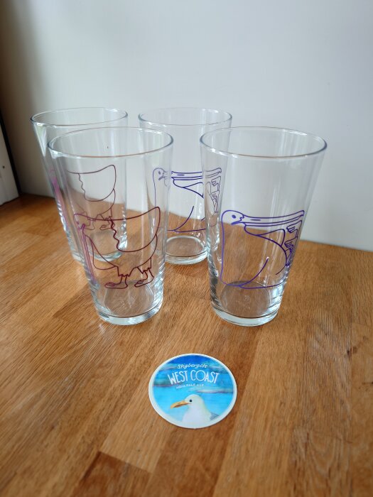 Fyra glas med tecknade måsar och en ölunderlägg märkt "West Coast IPA".