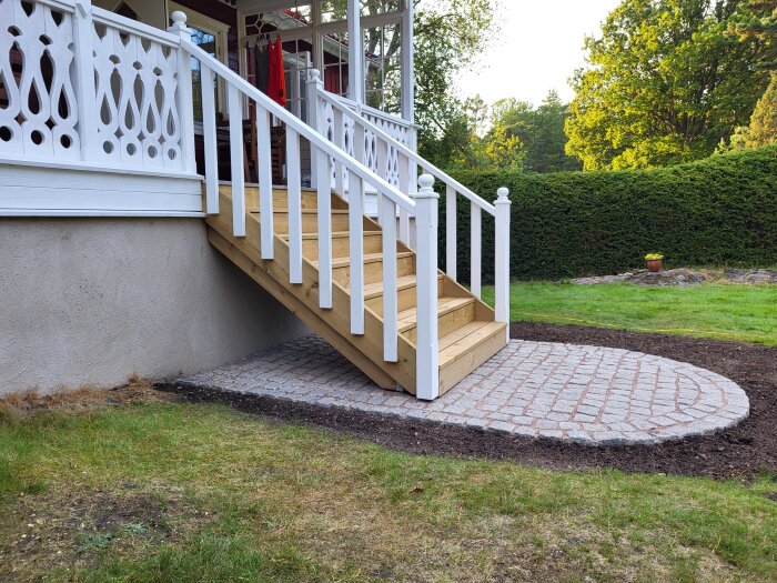Trappa med nyligen monterade staketribbor och stenlagd yta framför.