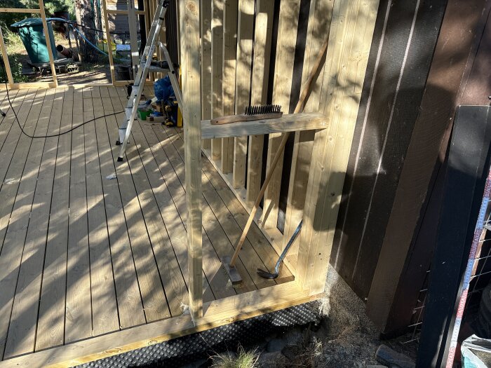 Träram och veranda under konstruktion med stege och diverse verktyg.