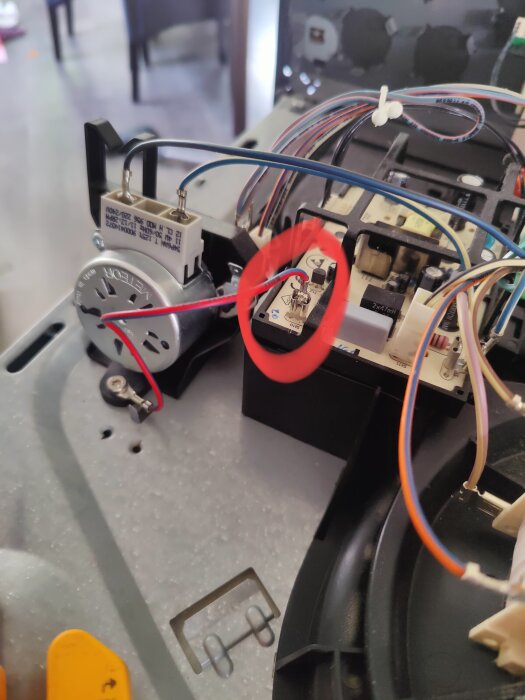 Kretskort med markerat jordstift omgiven av kablar och komponenter, identifierad kortslutning enligt text.