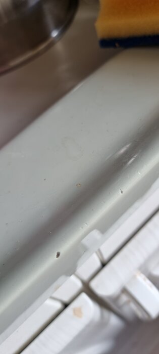 Arbetsbänk av emaljbeklädd glasfiber med några skavanker och en gul diskborste syns ovanpå ytan.