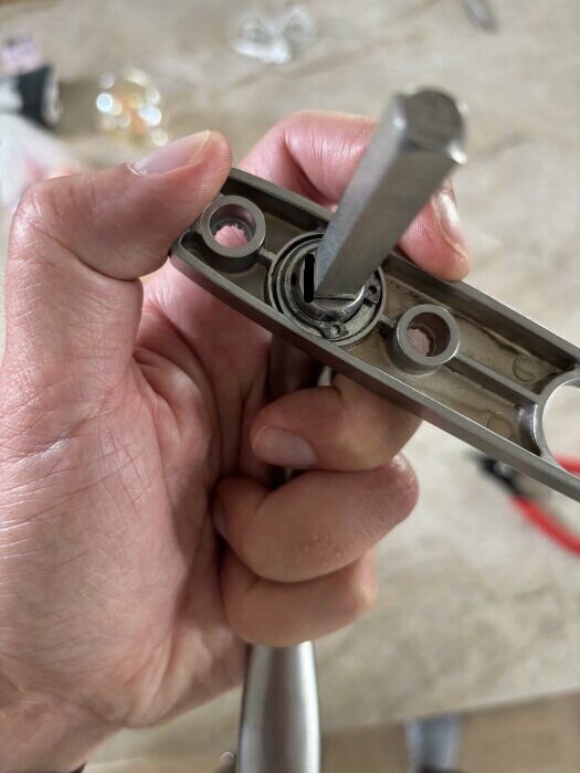 Hand håller i handtag och fyrkantspinne medan en skruvmejsel används för att knacka ur pinnen vid markering.