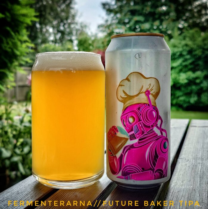 En ölburk med futuristiskt robottema och ett glas gyllene öl på ett bord utomhus.