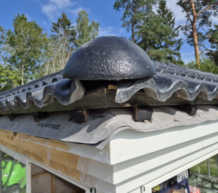 Valmat tak med nockpanna monterad på nockens börjanvalm, svart och vågig design, frågor om installation och estetik.