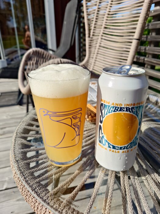 Ett glas öl från Stigbergets på ett bord utomhus, bredvid en burk med etiketten "Stigbergets Göteborg India Pale Ale".