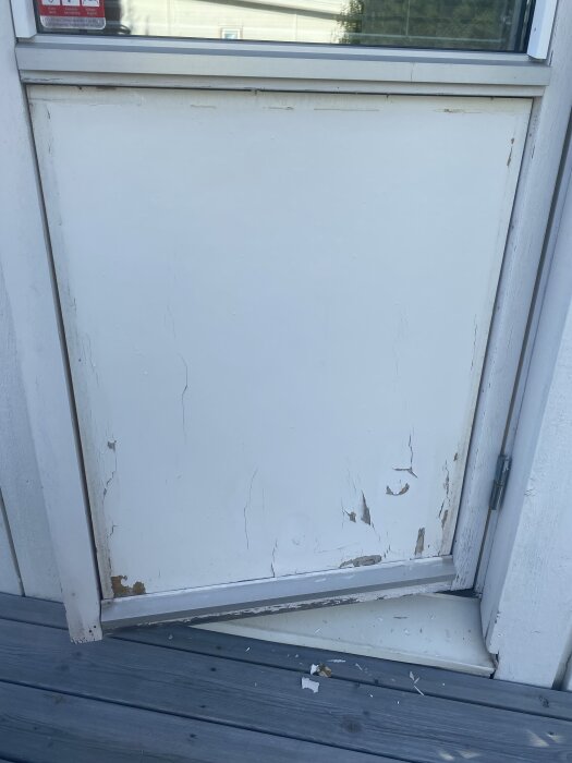 Altandörr med skadad nedre del och avlägsnade lister, svår att lossa.