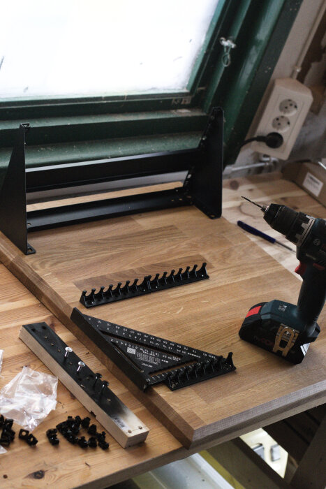 Montering av serverrack på ekskiva med borrmaskin, montageskruv, vinkellinjal och kabelfästen på arbetsbord.