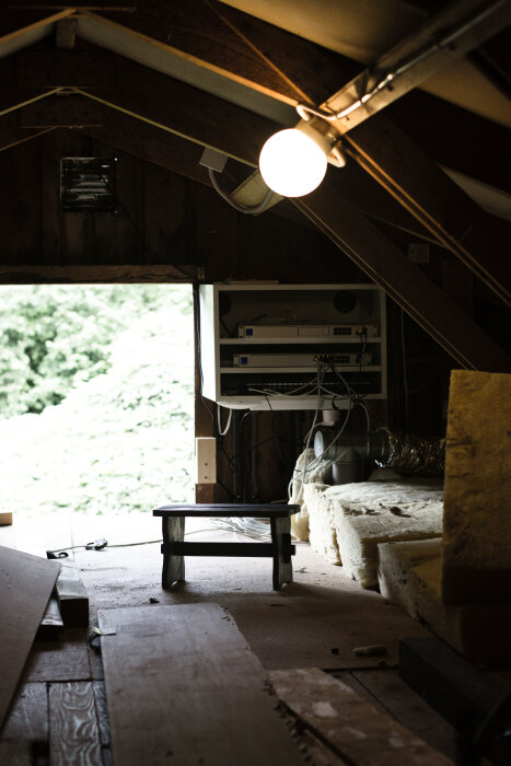 En upplyst vind med ett serverrack monterat på väggen, omgiven av kablar och isoleringsmaterial.