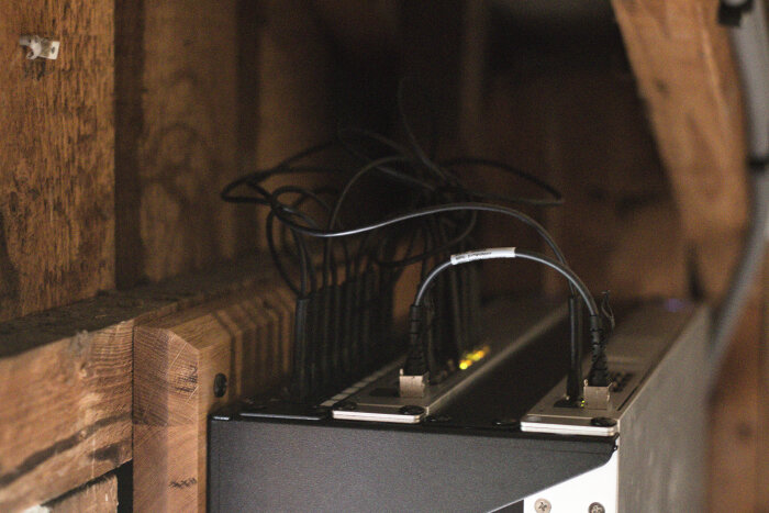 Serverinstallation uppe på en vind, med rackmonterad patchpanel, switch och routrar. Kablar syns kopplade och delvis oorganiserade.