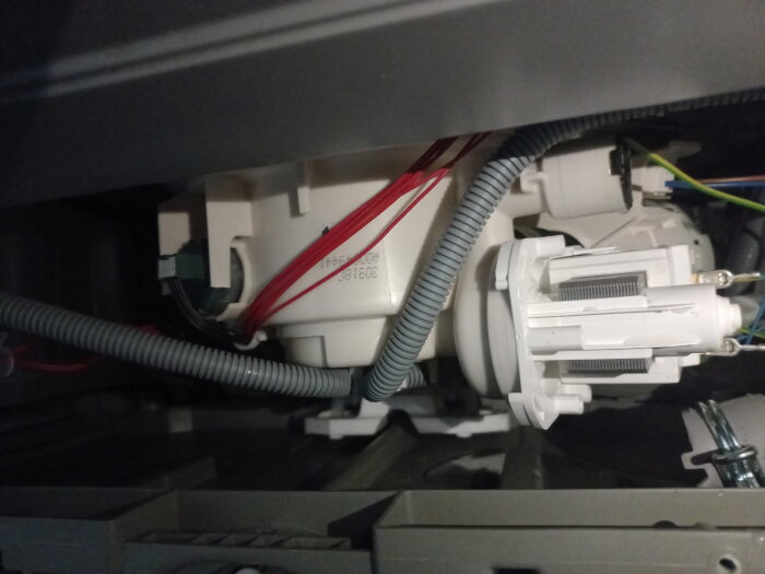 Diskmaskinens insida som visar slangar och pumpmekanik, med fokus på en misstänkt blockerad pumpdel.