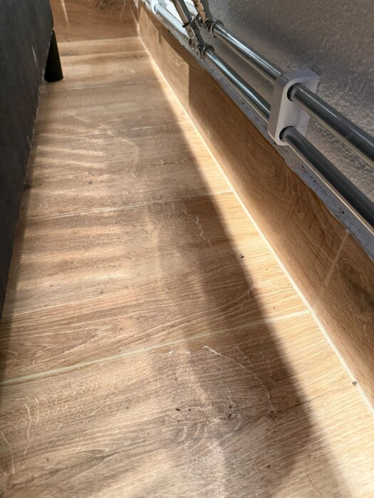 Klinkergolv med kondensvatten och rör längs väggen i en källare.