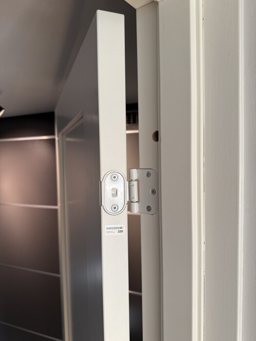 Innerdörr med gångjärn från Swedoor, delvis öppen och fäst i karmen, visar snäpplås och konstruktion.