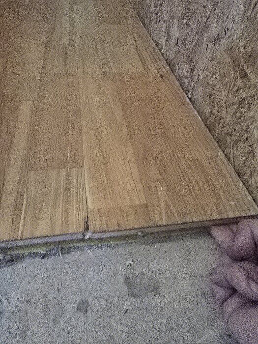 Trägolv hålls upp, tycks vara limmat fast i underlaget.