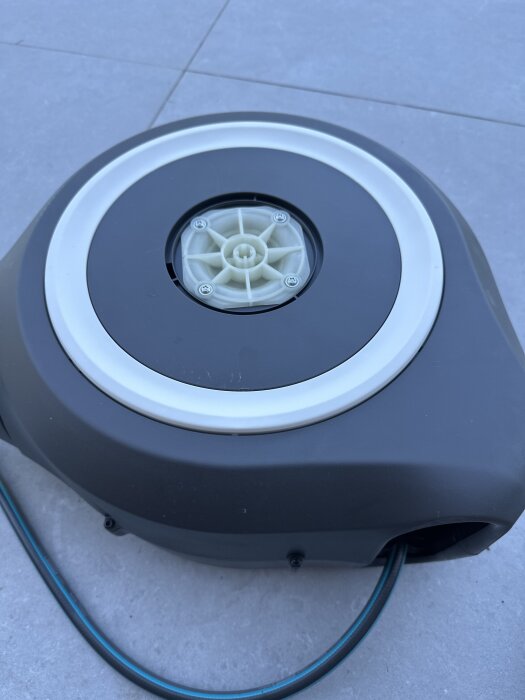 Slangvinda med synlig säkerhetstorx och slangfäste på stengolv.