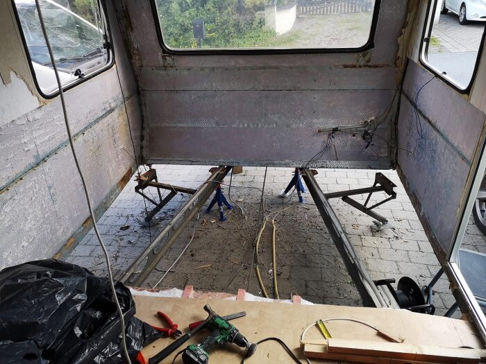 Renovering av husvagn med borttagen inredning, synliga väggstommar och verktyg på golvet.