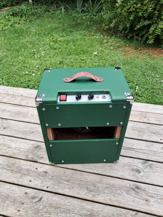 Grön rörförstärkare i 10" öppen combo med älgskinnshandtag och stålremsa på verandagolv.