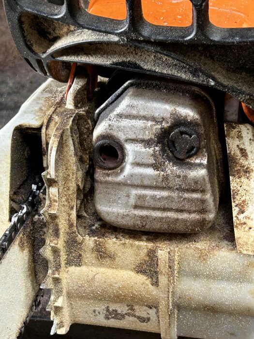 En närbild av en motorsåg täckt med sågspån, vilket visar slitage och smuts efter användning.
