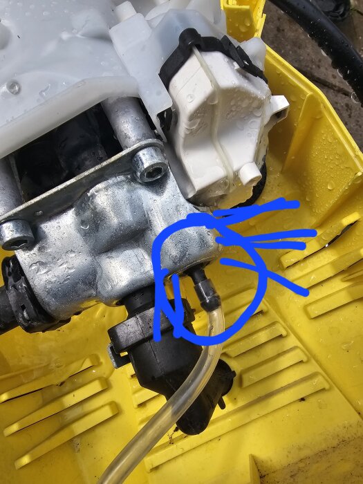 Närbild av insidan på en högtryckstvätt med ett markerat område kring en plastslang och anslutning.