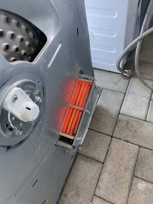 Värmeelementet i en öppen torktumlare med glödande röda trådar.