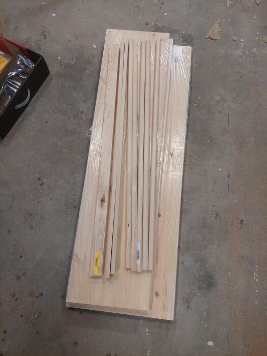 Planhyvlat trä och rundstavar ligger på ett betonggolv, redo för byggprojekt.