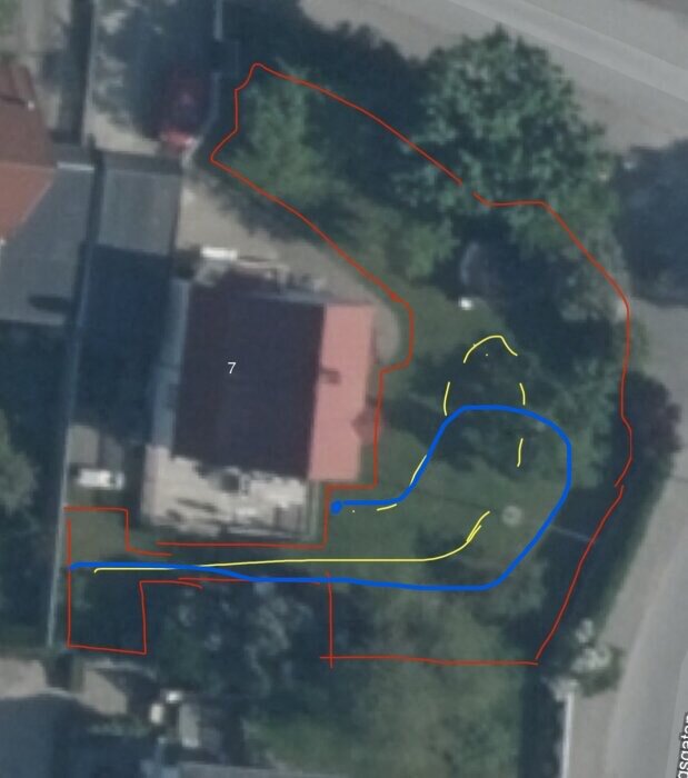 Flygbild över en trädgård med markerade linjer: en röd gräns, en blå ballongformad sväng och gula slingor nära träd omgivna av kullersten.