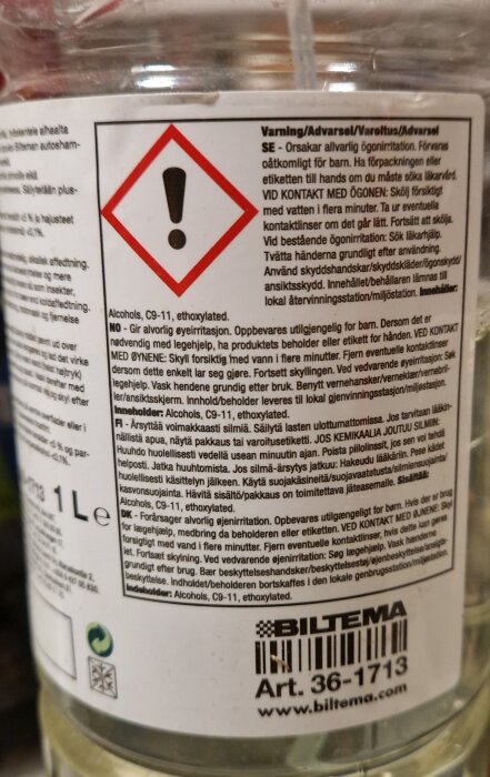 Närbild av etiketten på en Biltema bioavfettning-flaska med varningstext på flera språk och en symbol för försiktighetsåtgärd.